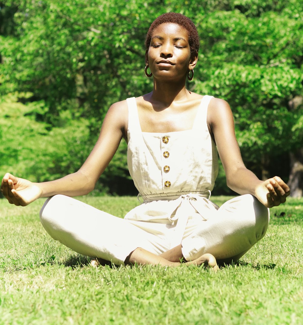 woman in white tank top sitting on green grass field during daytime