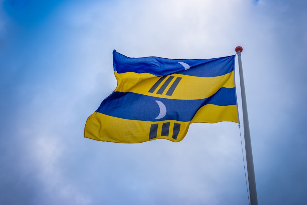 Foto zum Thema Gelb-blau gestreifte Flagge unter blauem Himmel tagsüber –  Kostenloses Bild zu Flagge von Ameland auf Unsplash