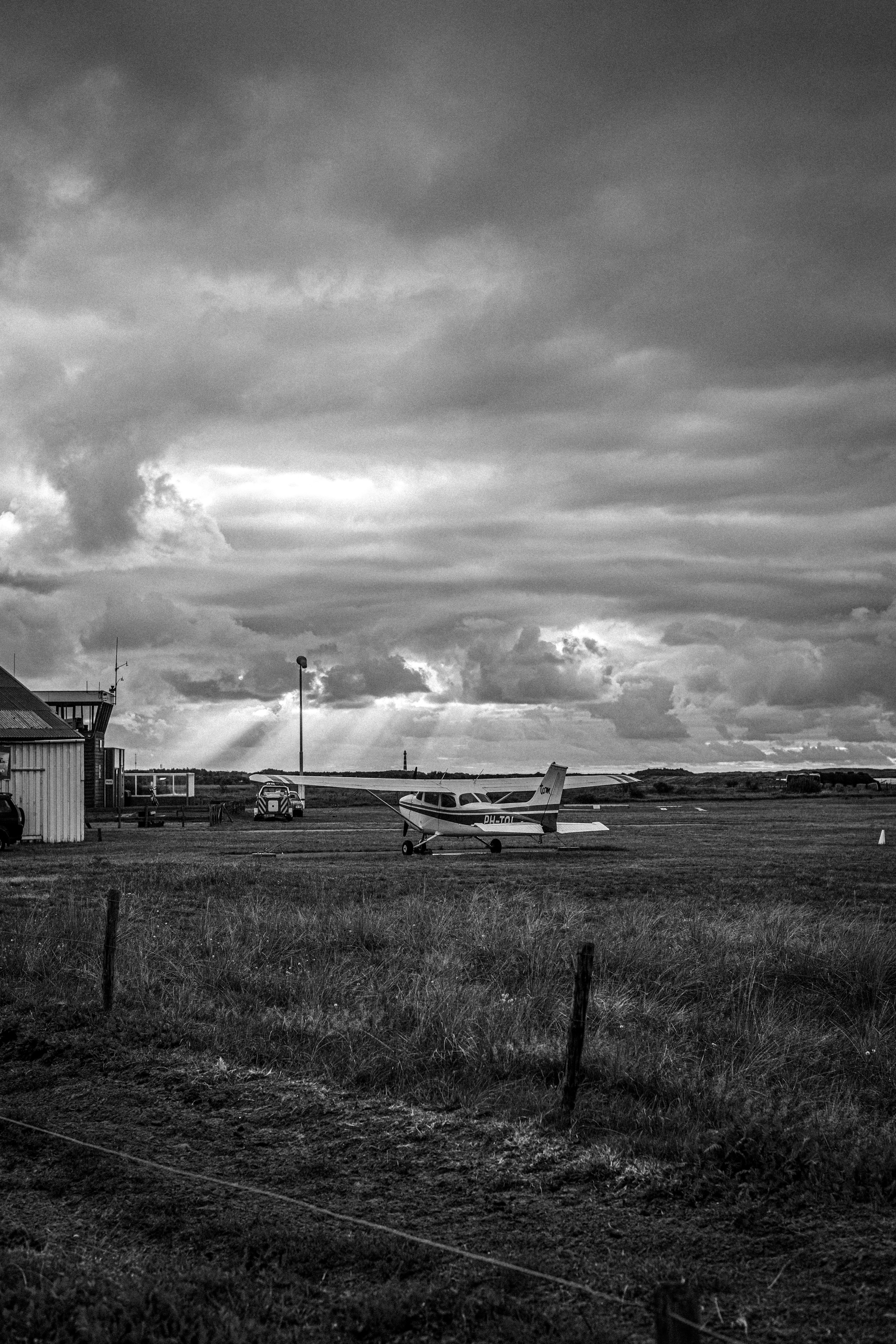 Photo en niveaux de gris d’une maison en bois sur un champ d’herbe