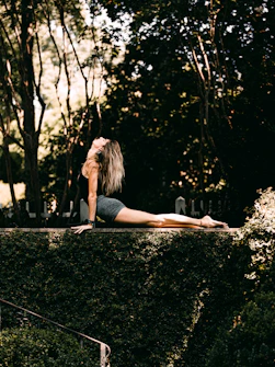 woman in black tank top and black shorts sitting on black asphalt road during daytime