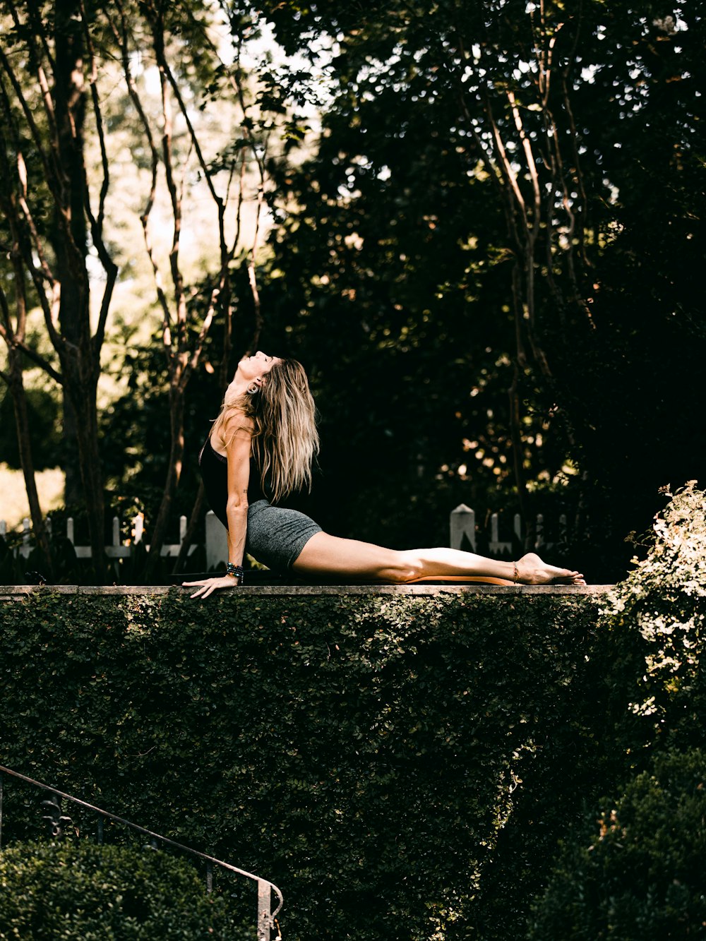 woman in black tank top and black shorts sitting on black asphalt road during daytime