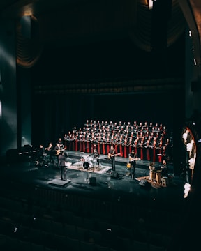 people standing on stage in front of red curtain