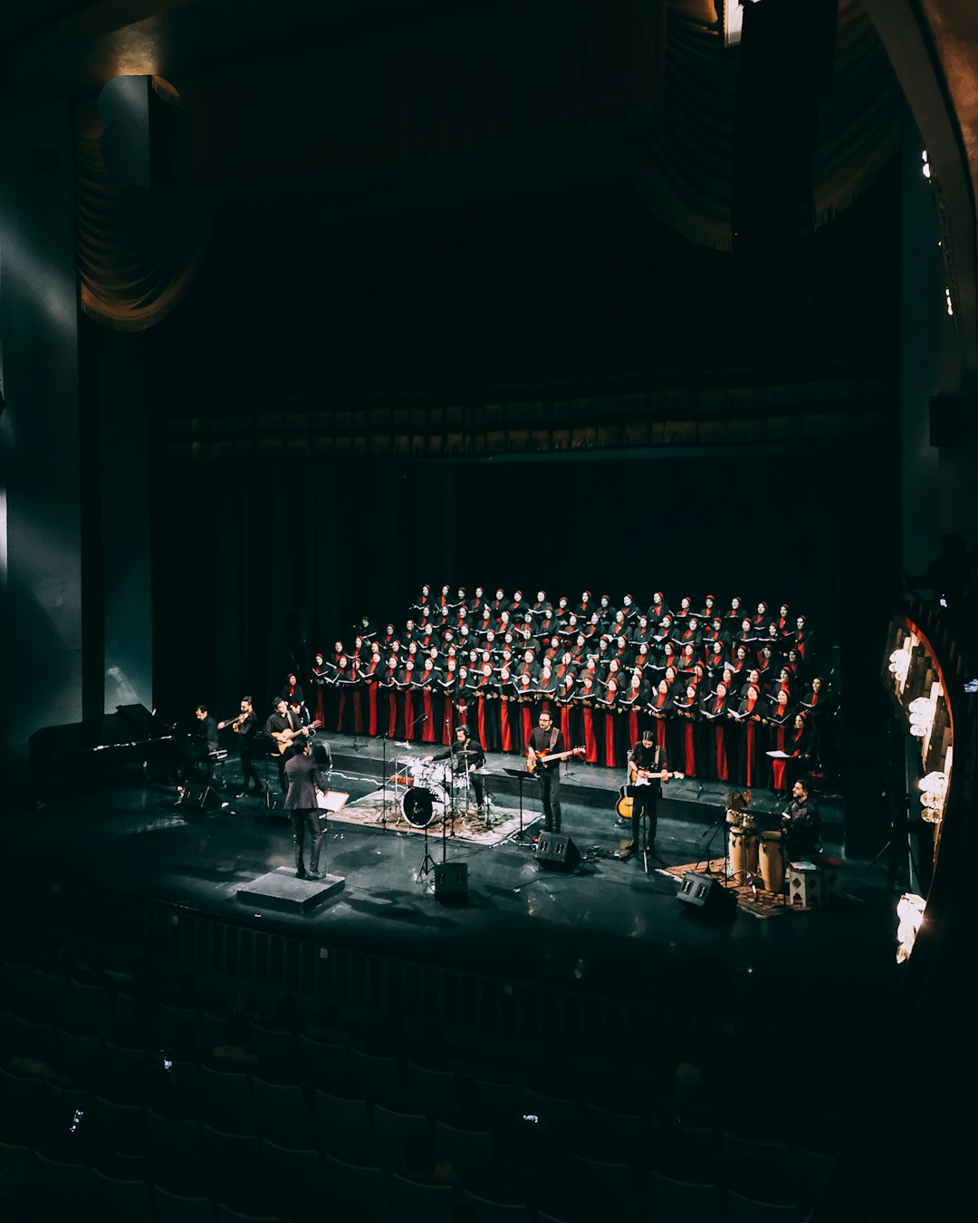 people standing on stage in front of red curtain