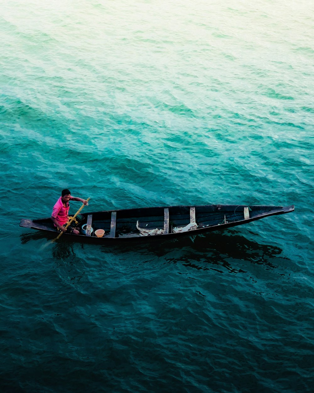 man in red shirt riding on boat during daytime