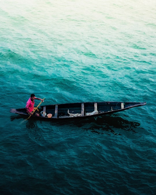 man in red shirt riding on boat during daytime in Sylhet Bangladesh