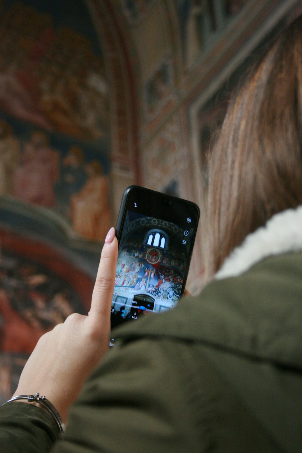 woman in white fur jacket holding black iphone 5