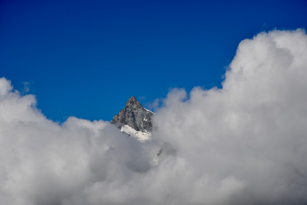 a mountain in the clouds with a blue sky in the background