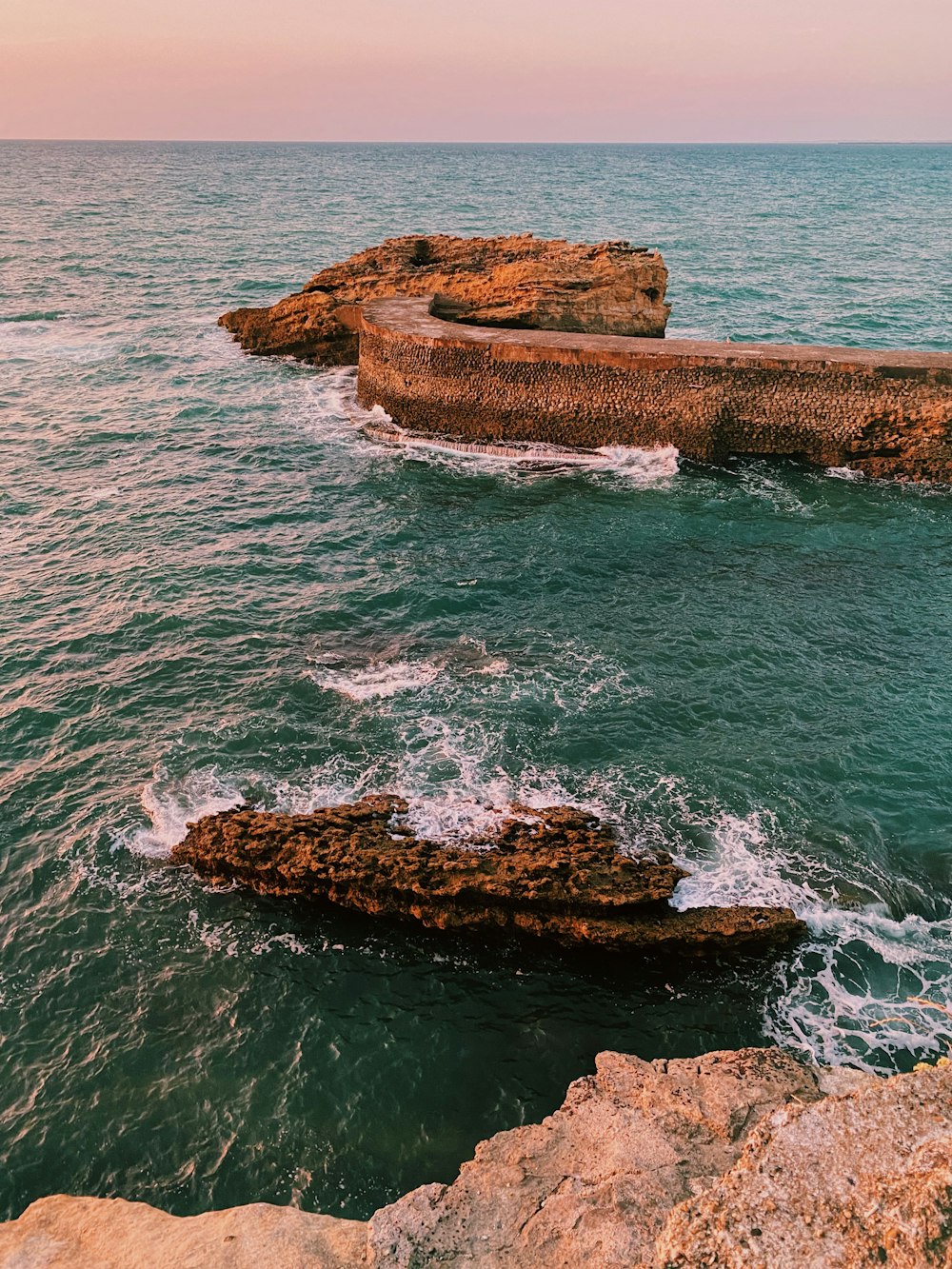 brown rock formation on body of water during daytime