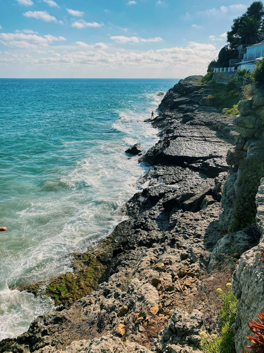 rocky shore with ocean waves crashing on rocks during daytime