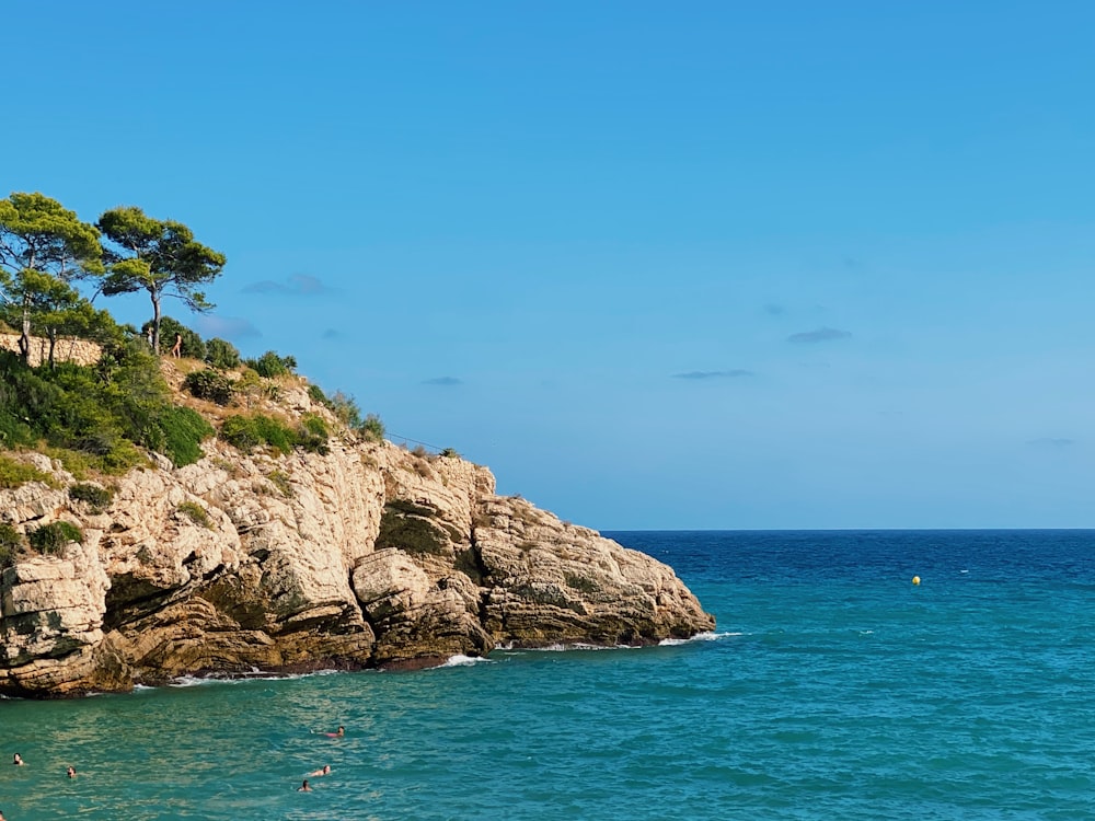 brown rocky mountain beside blue sea under blue sky during daytime