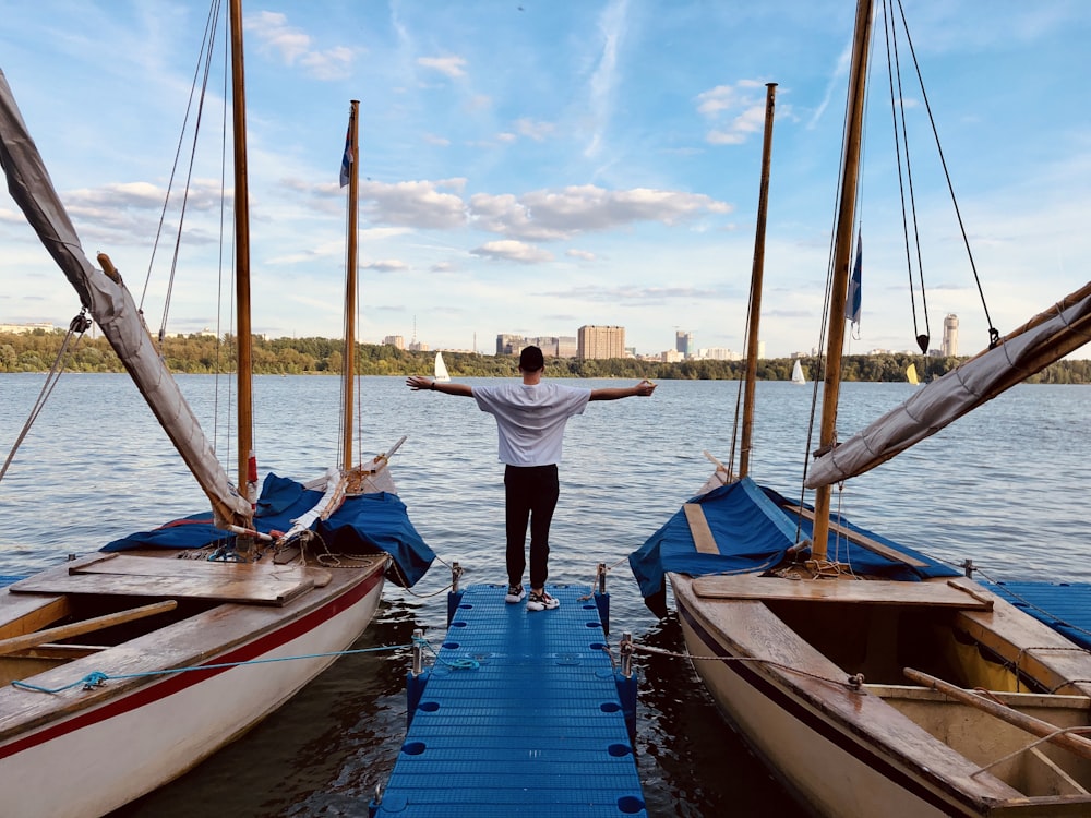 man in white shirt and blue denim jeans standing on blue and white boat on sea