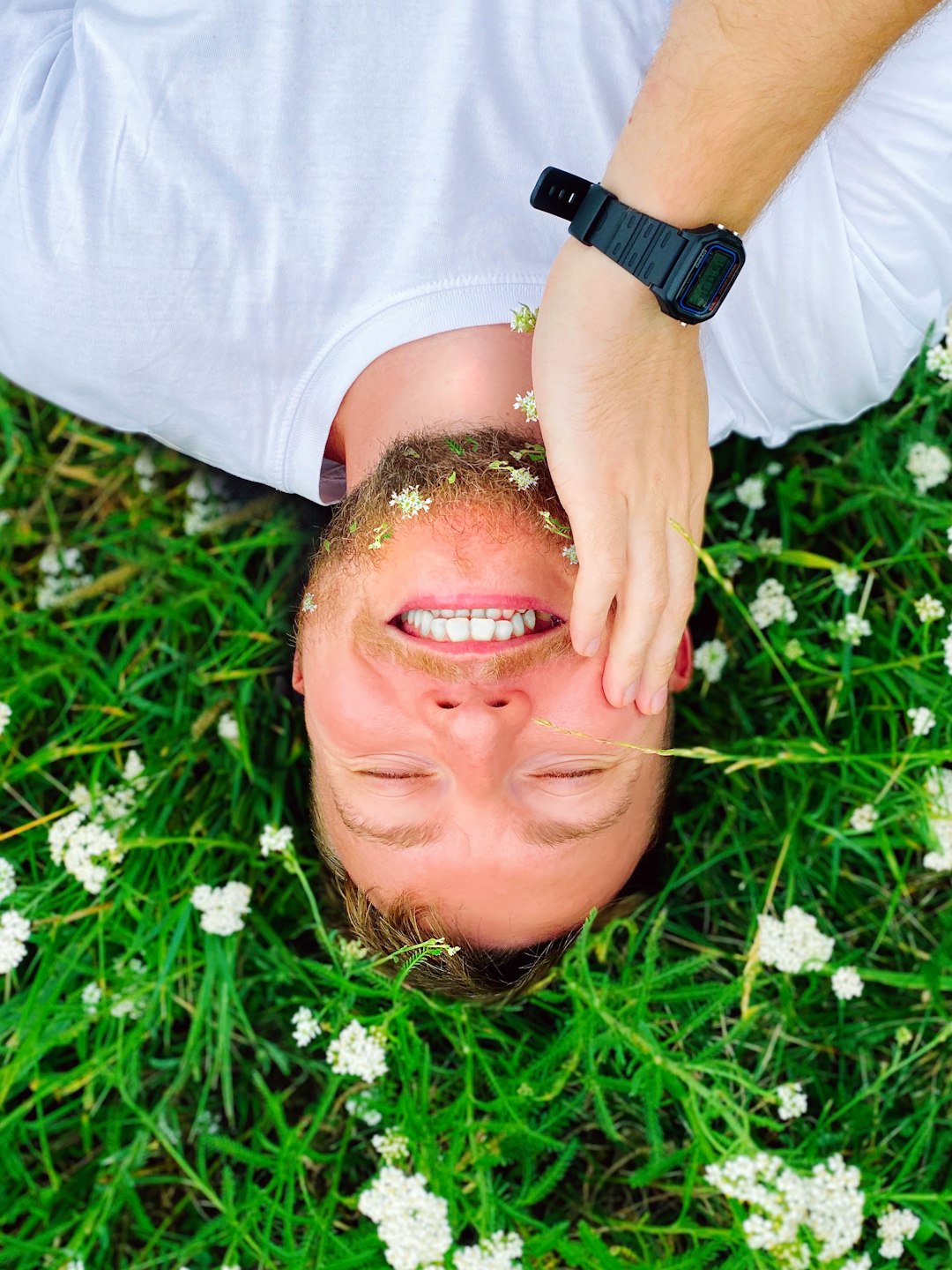 man in white crew neck shirt lying on green grass