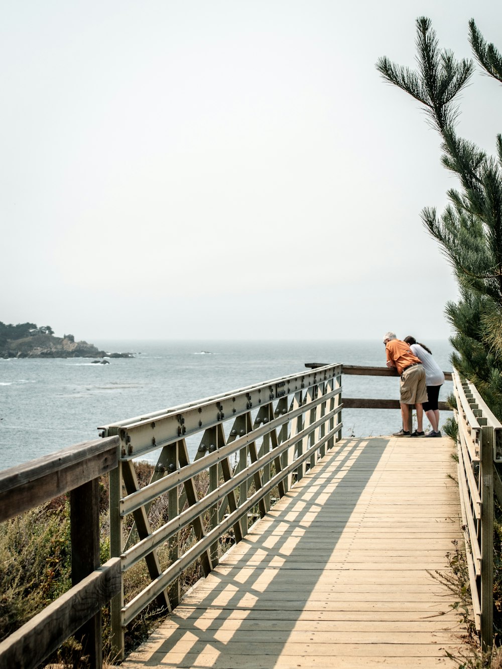 woman in white shirt and black pants walking on wooden bridge during daytime