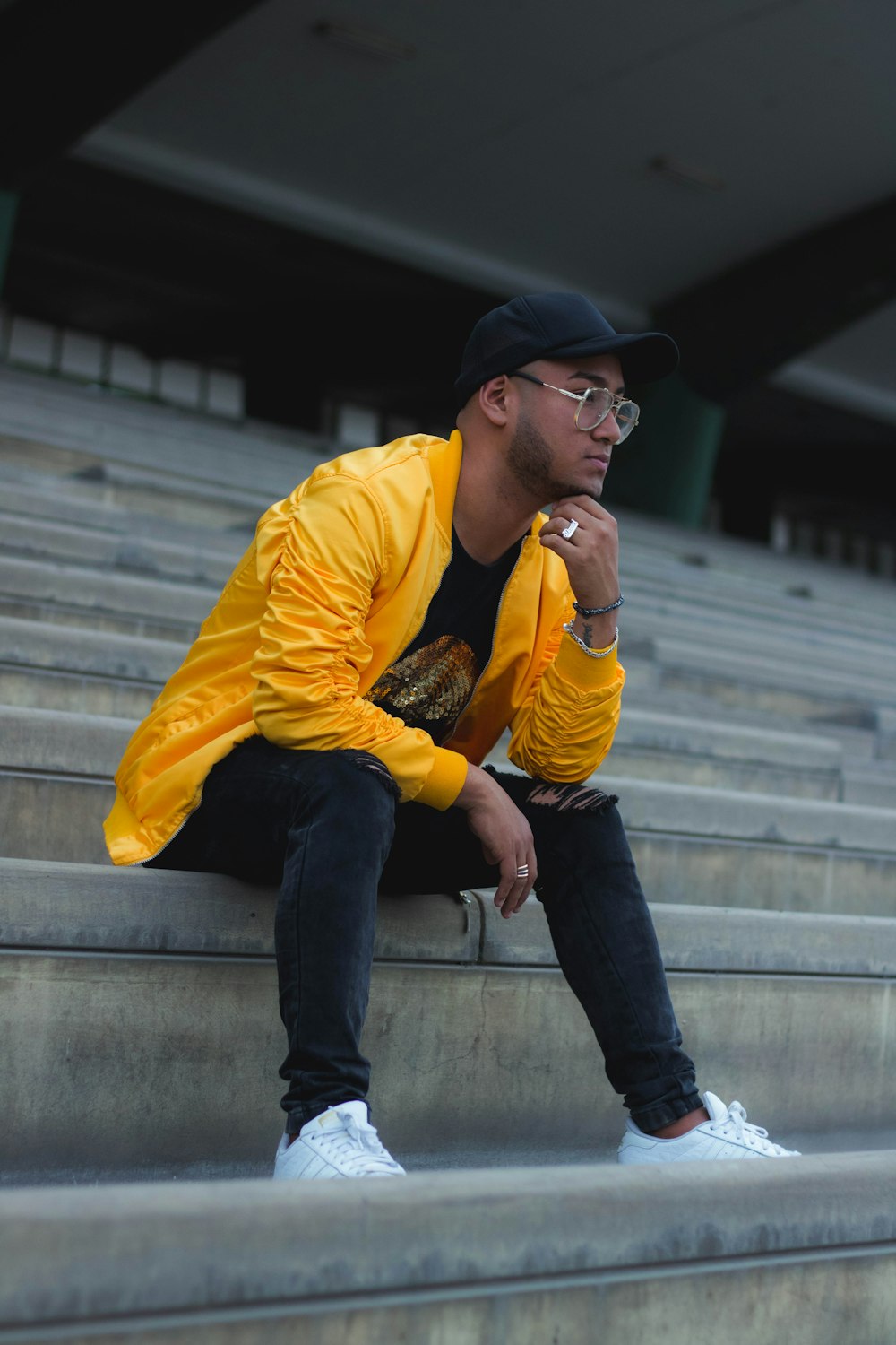 man in yellow dress shirt and blue denim jeans sitting on concrete stairs