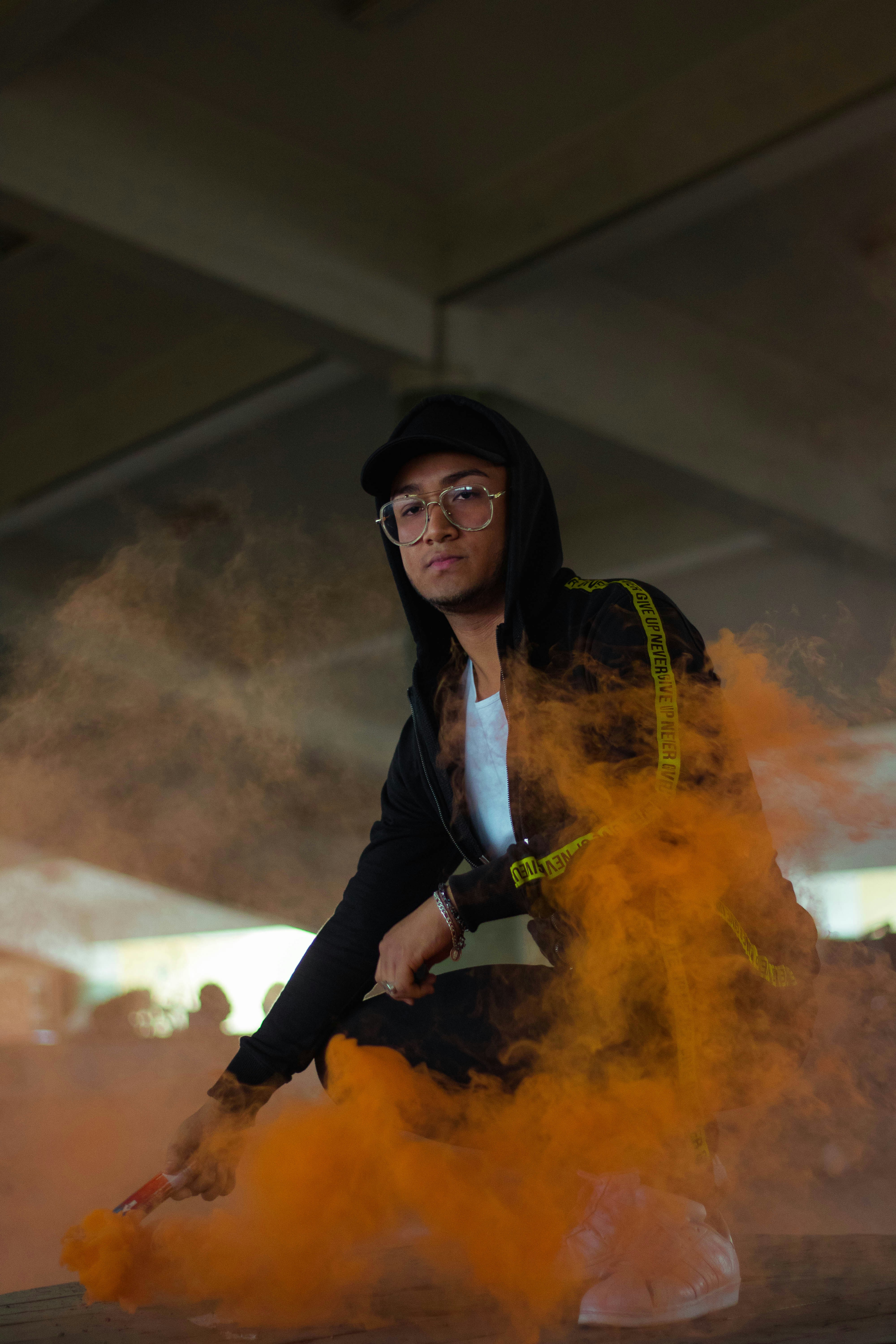 wanita berjaket hitam dan celana hitam dengan asap kuning di wajahnya