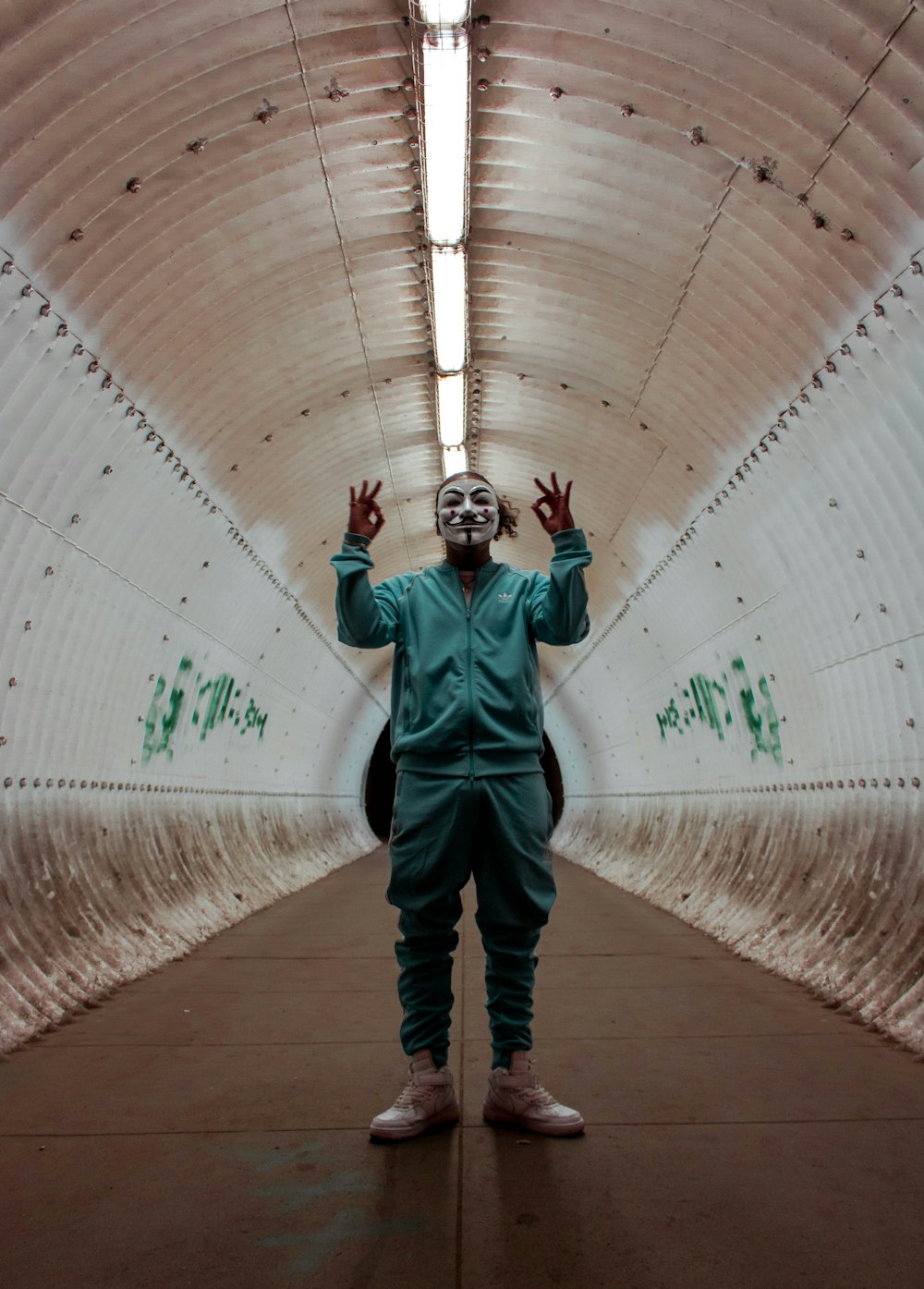 man in green jacket and black pants walking on tunnel