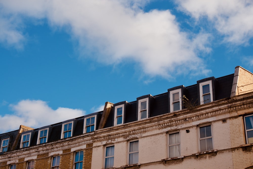 brown concrete building under blue sky and white clouds during daytime