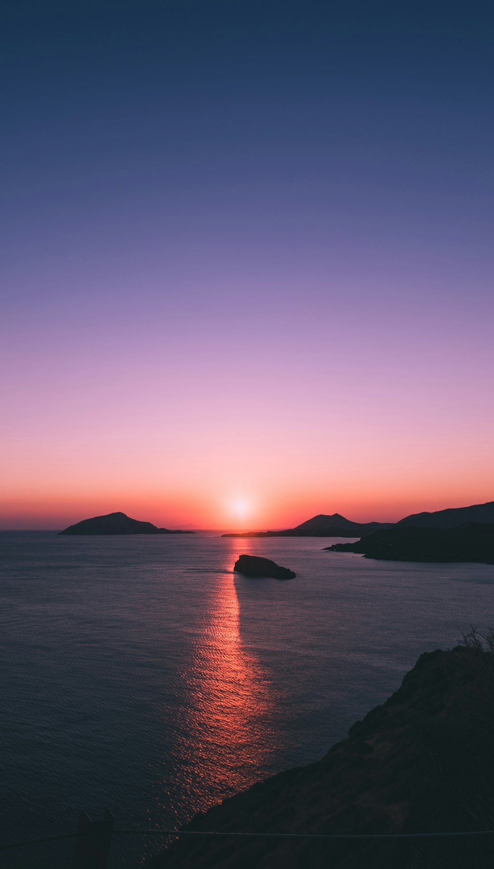 silhouette of mountain beside sea during sunset