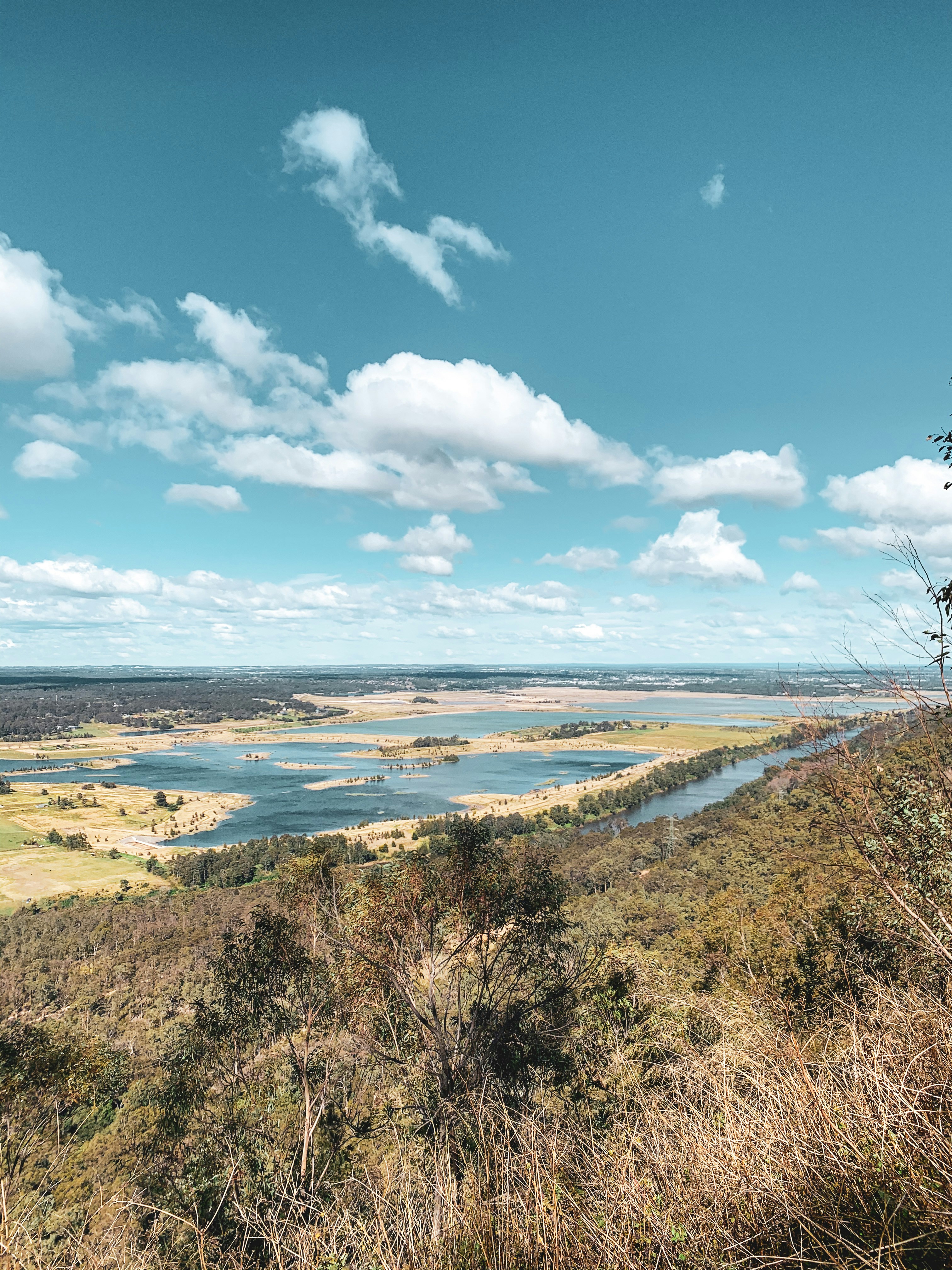 campo de grama verde perto do corpo de água sob o céu nublado azul e branco durante o dia