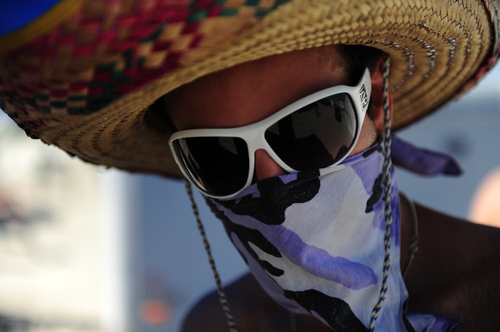 person wearing white framed sunglasses and brown straw hat