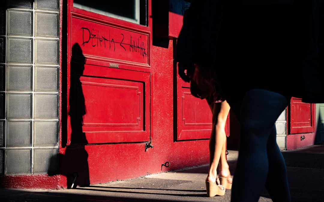 woman in black tank top and black shorts leaning on red wooden door