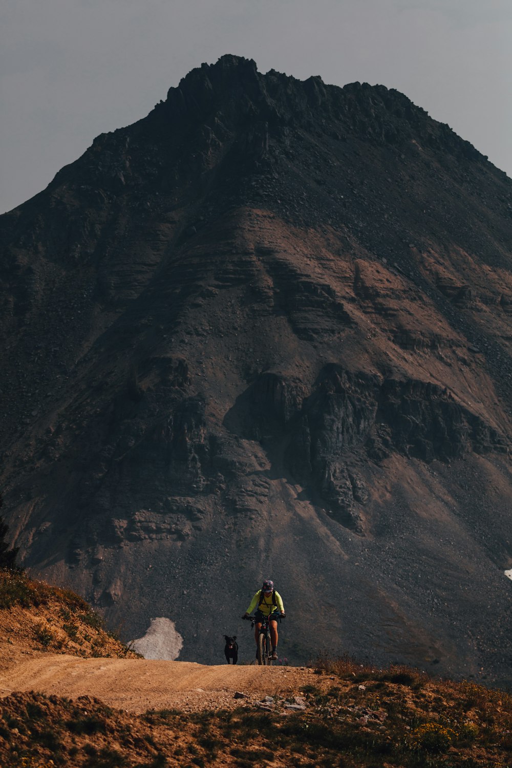 Persona in giacca gialla in piedi sulla montagna rocciosa durante il giorno