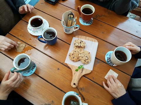 A collection of personalized stainless steel mugs and coasters arranged on a wooden table.