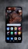 A smartphone displaying a home screen with various app icons, including Gallery, Play Store, File Manager, and Music. The background features a textured, earthy design. The time reads 10:46 and the date is displayed as Thursday, August 20. The top right corner shows a weather widget with a sun icon and a 'No data' label.