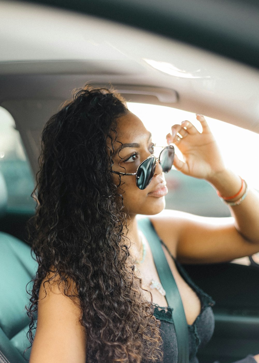 woman in green tank top holding black sunglasses