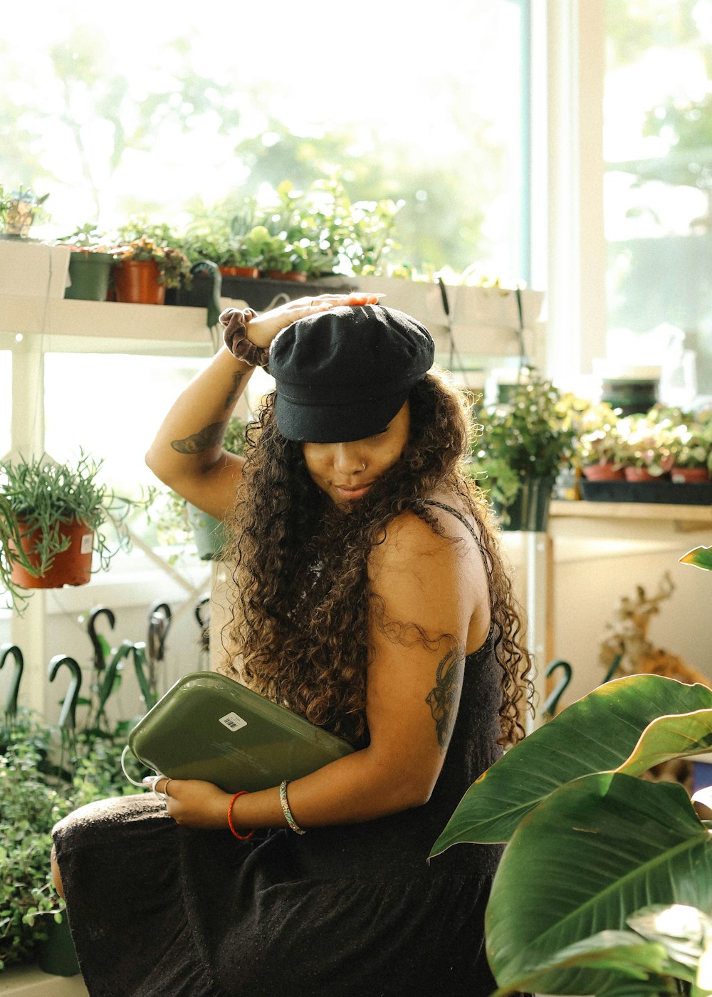 woman in brown tank top and black cap holding black tablet computer