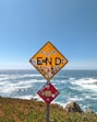 yellow and black road sign near sea during daytime