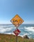 yellow and black road sign near sea during daytime