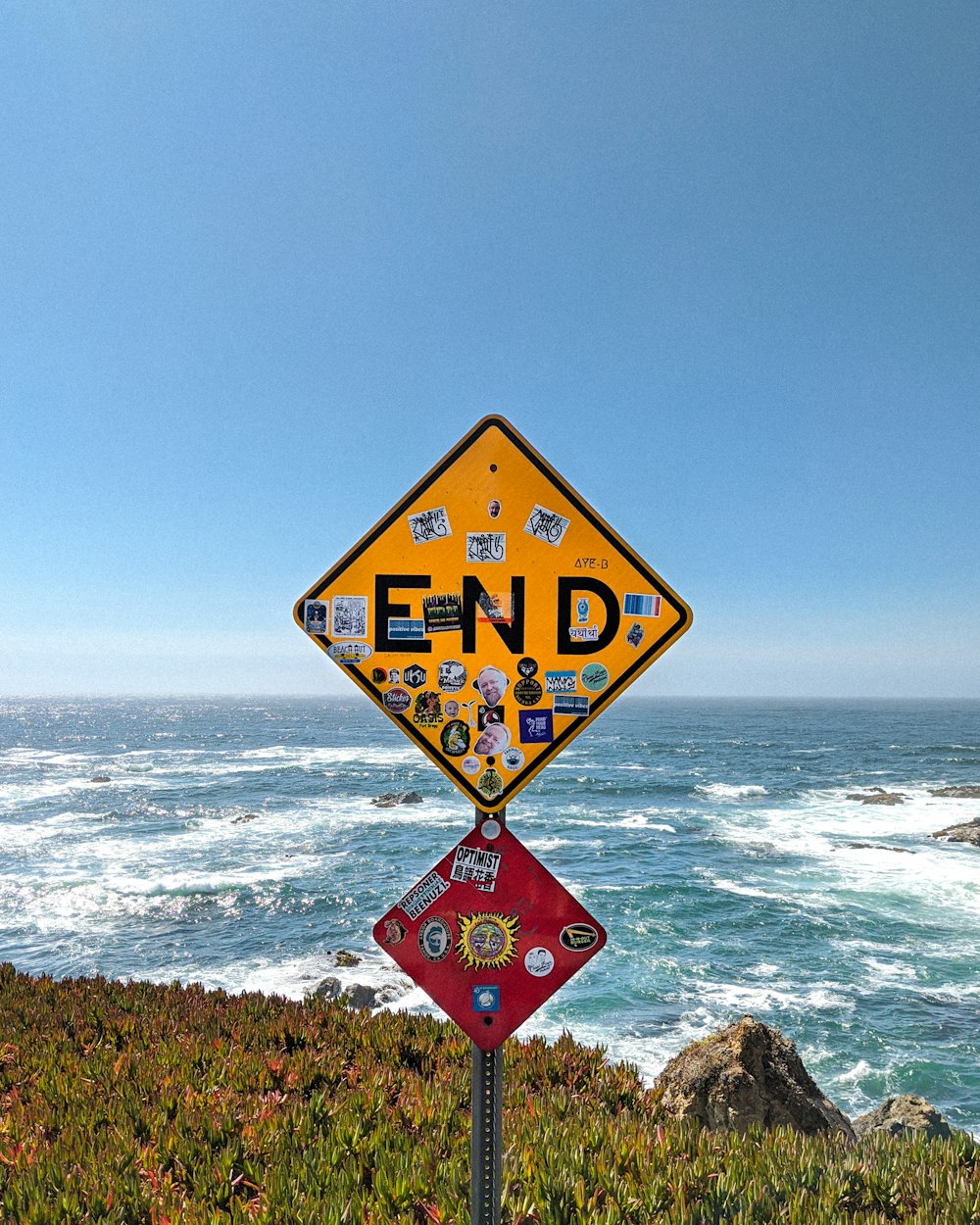 Panneau de signalisation jaune et noir près de la mer pendant la journée