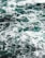 Waves of the ocean create a turbulent pattern on the water's surface, with foamy white crests contrasting against the deep teal of the sea.