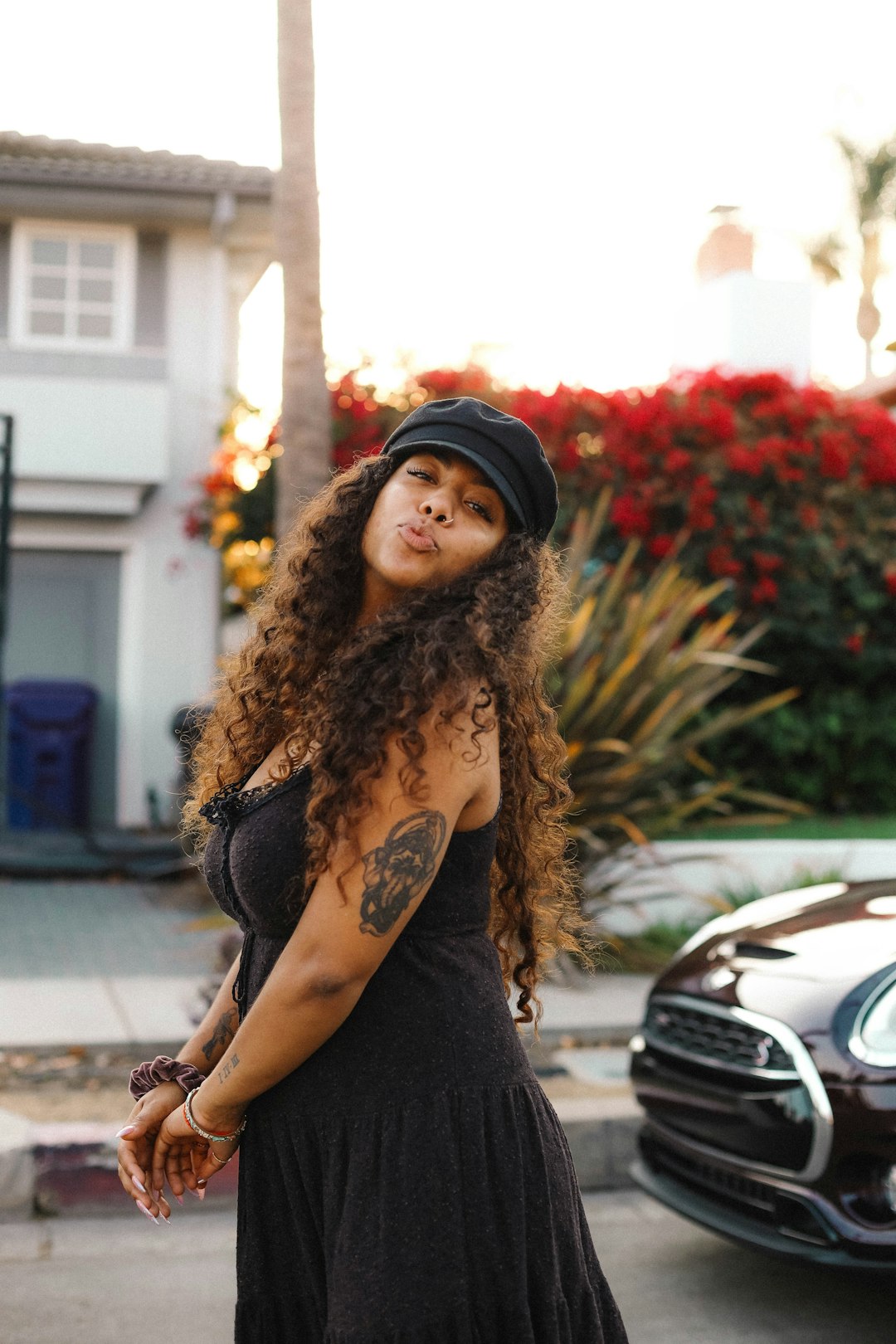 woman in black long sleeve shirt and black knit cap standing near red car during daytime