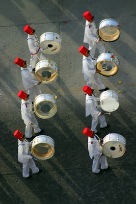 a group of men in white uniforms playing drums