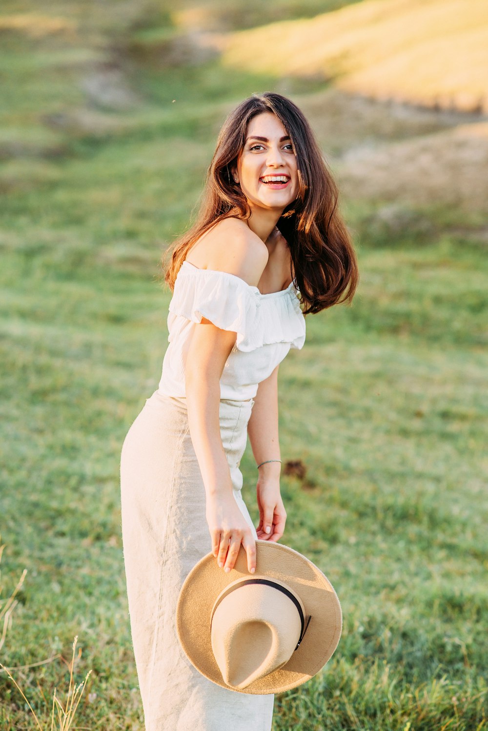 woman in white dress holding brown hat