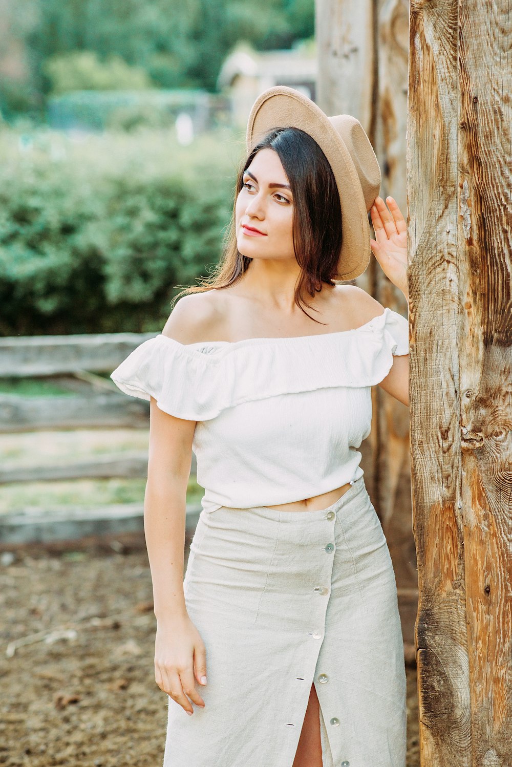 woman in white shirt leaning on brown wooden post during daytime