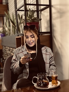 A smiling person reviewing their monthly budget on a tablet with a cup of tea nearby.