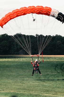 2 men in red and black suit riding on yellow and red parachute