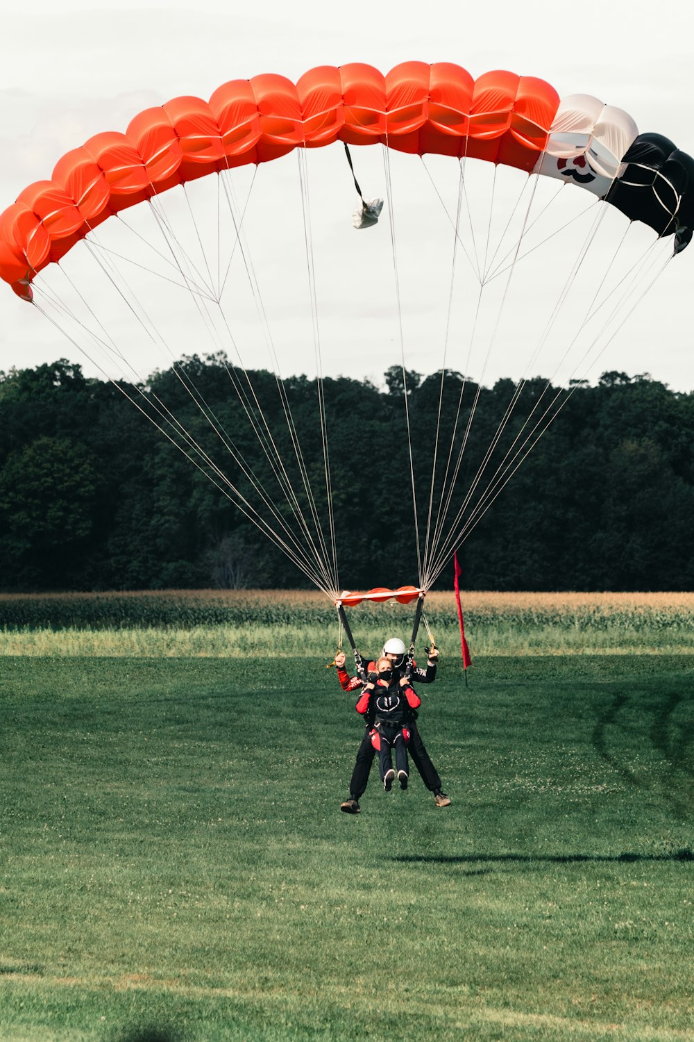 2 men in red and black suit riding on yellow and red parachute