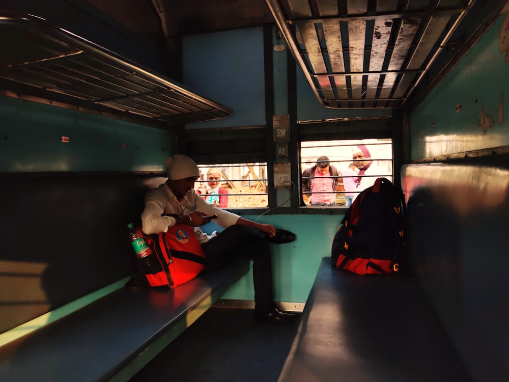 man in black jacket sitting on red bench