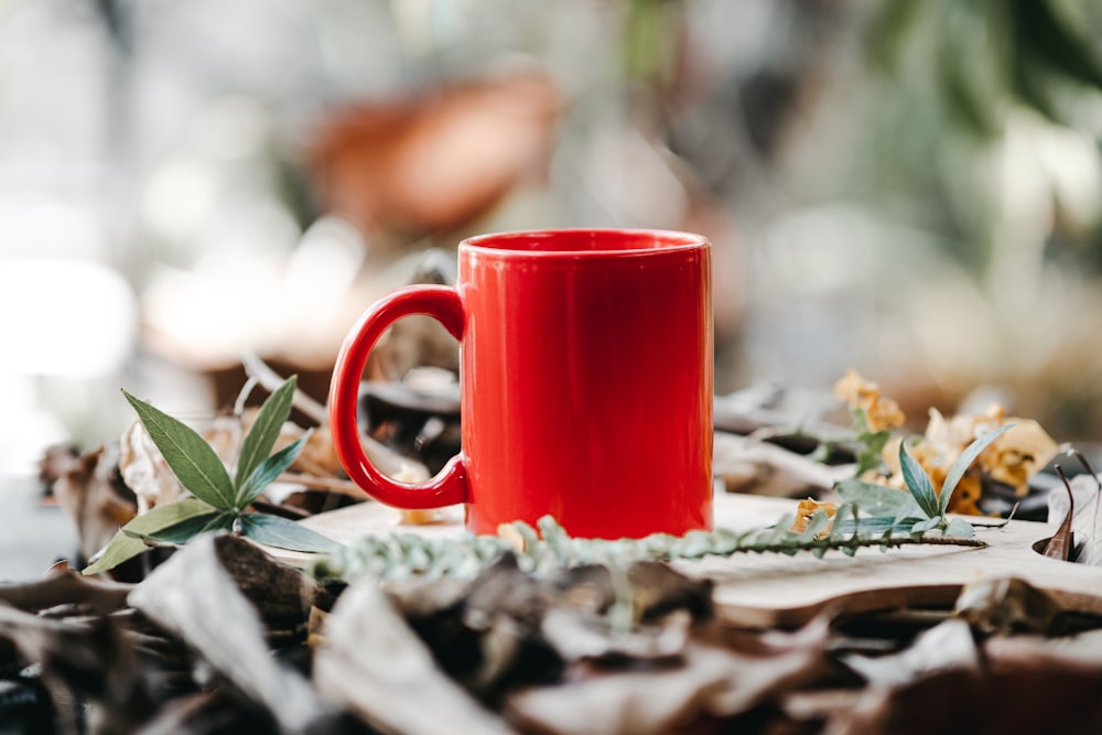 red ceramic mug on white textile