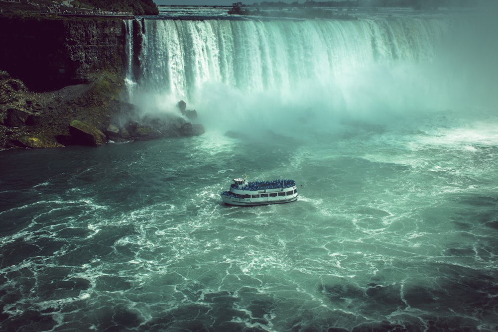 white and black boat on water falls