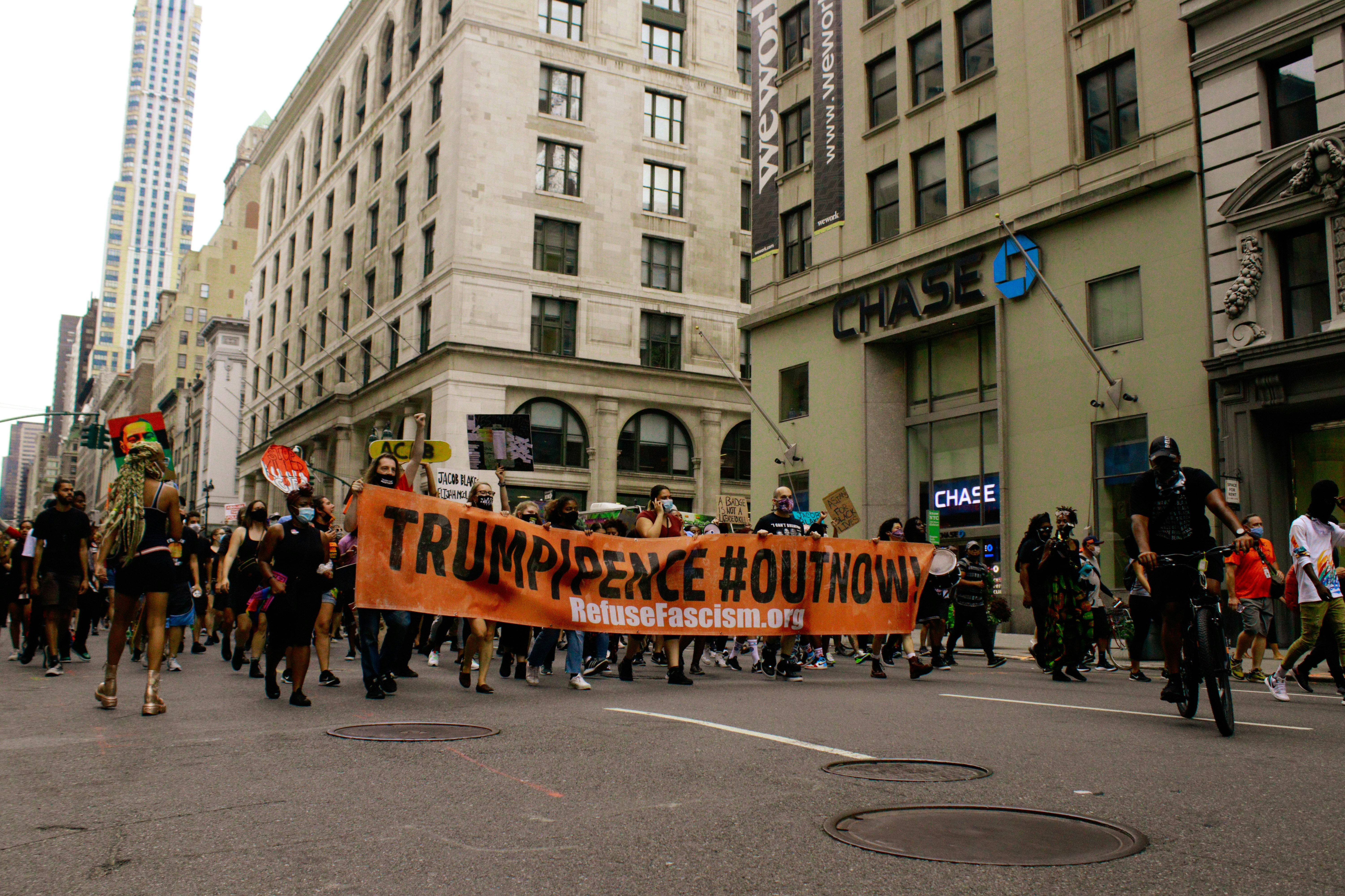 people walking on street with yellow and black banner during daytime