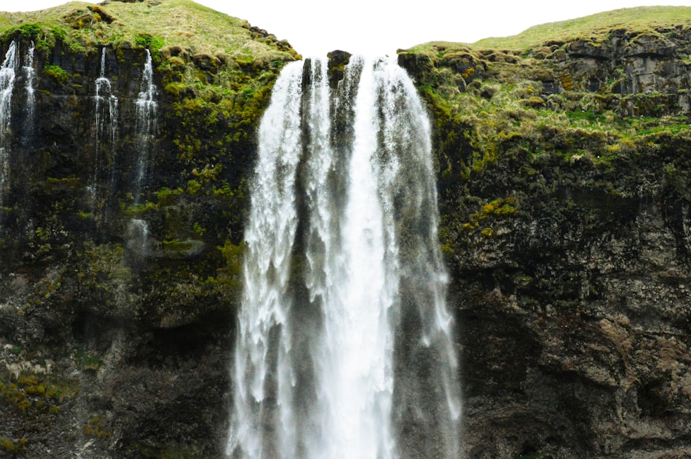 waterfalls on green grass field during daytime