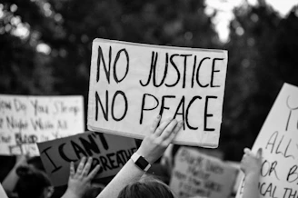 Close-up of hands holding protest signs demanding justice and transparency.