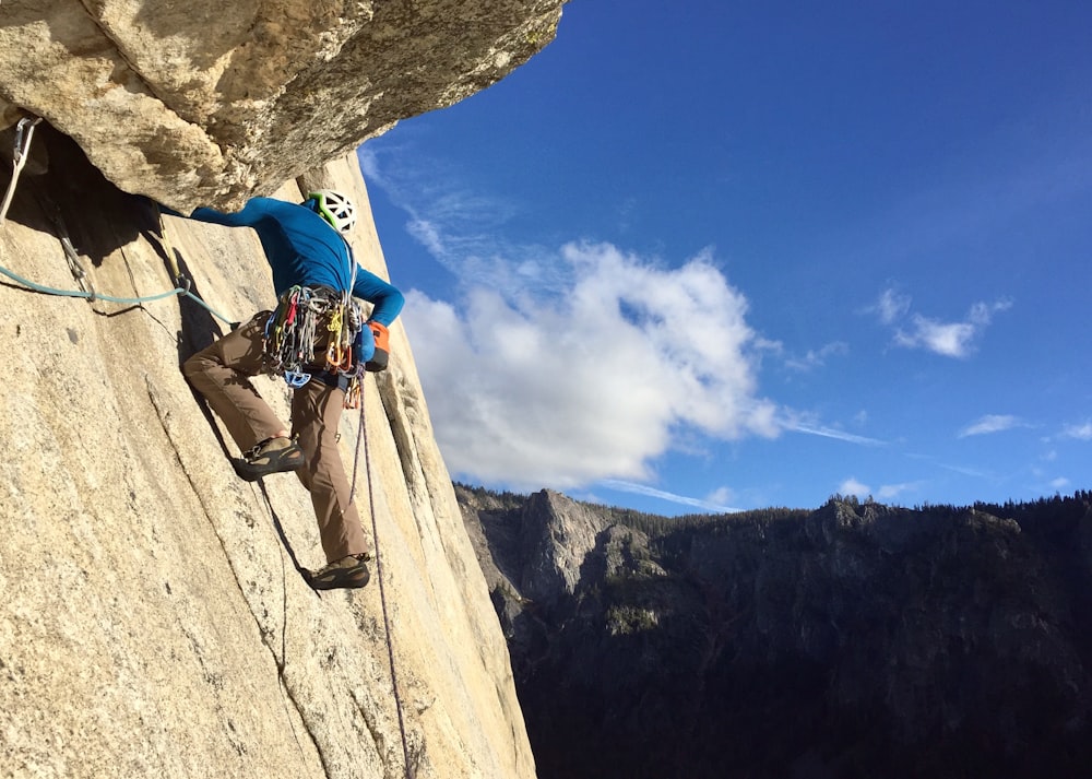 man in blue shirt climbing mountain during daytime