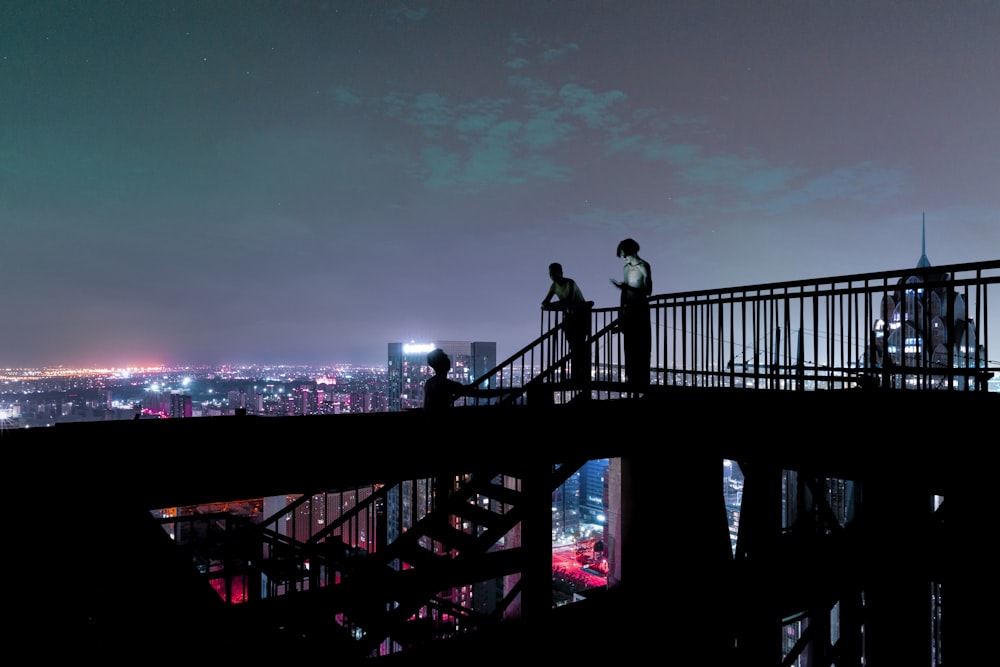 silhouette of man standing on bridge during night time
