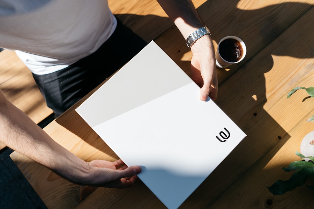 person in white shirt and black shorts holding white paper